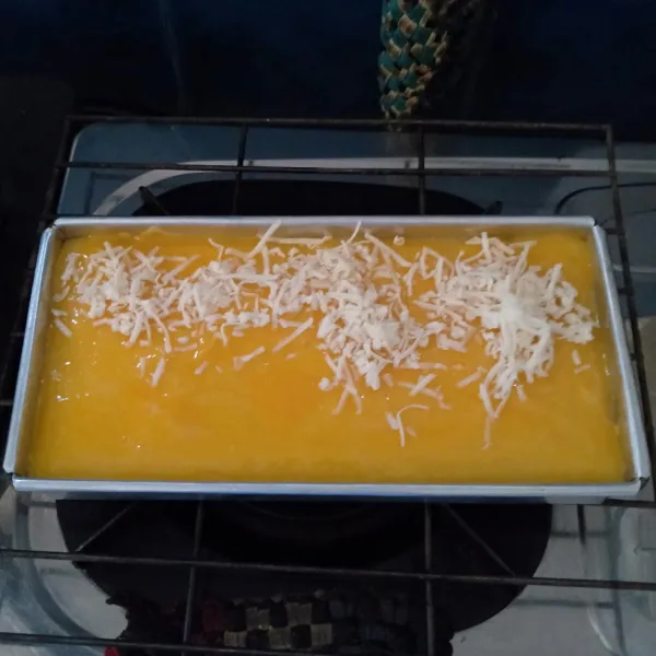 Keluarkan loyang dari oven dan oles dengan kuning telur lalu tabur keju dilanjutkan kismis.