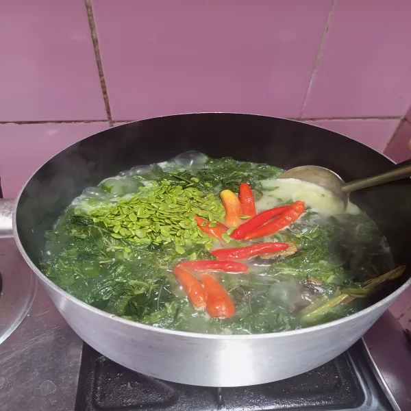 Masukkan santan kental, lalu aduk rata. Tambahkan cabai rawit merah dan petai cina, lalu aduk rata kembali.