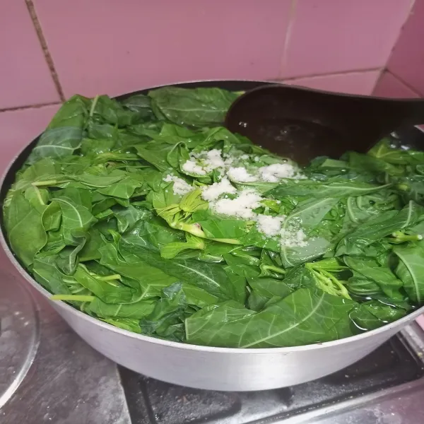Rebus daun singkong di air mendidih yang diberi sedikit garam hingga empuk, lalu tiriskan dan iris. Kemudian sisihkan.