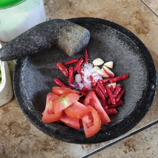 Haluskan (ulek) cabai merah keriting, bawang merah, bawang putih, dan tomat, lalu sisihkan.