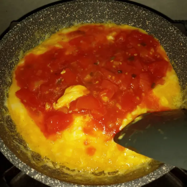 Selagi bagian atasnya masih basah, masukkan saus tomat yang dibuat tadi, tambahkan kaldu jamur. Masak sambil diaduk perlahan, hingga cukup matang, jangan sampai terlalu kering telurnya.