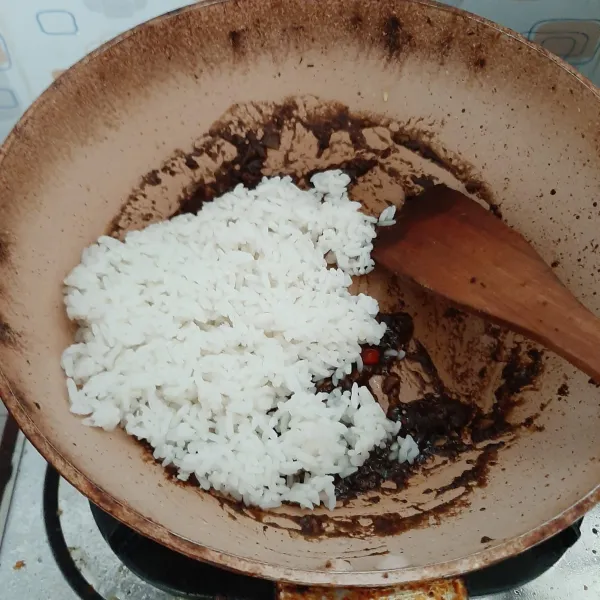 Masukkan nasi, beri garam dan kaldu bubuk lalu aduk rata.