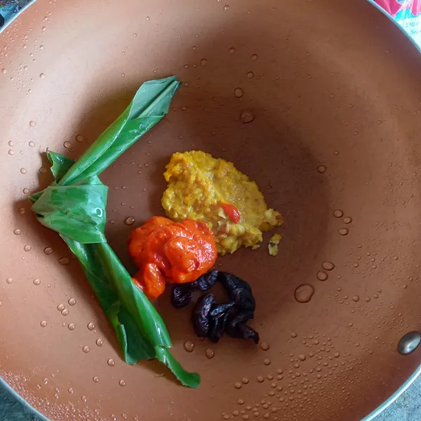 Masukkan bumbu yang sudah dihaluskan, cabai giling, daun kunyit, asam kandis ke dalam wajan.