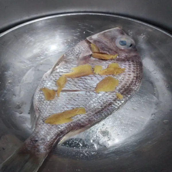 Siapkan ikan untuk dikukus, beri irisan jahe di bagian atas, dalam perut dan bagian dalam kepala, kukus selama 15 menit