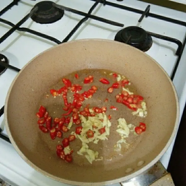 Goreng bawang putih dan cabai merah keriting hingga harum.