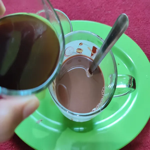 Salin minuman coklat ke dalam gelas yang lebih besar, kemudian tuang kopi ke dalam gelas yang berisi minuman coklat tersebut.