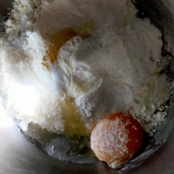 Siapkan wadah kemudian masukkan tepung terigu, kuning telur, gula pasir susu bubuk dan ragi instan. Uleni sambil dimasukkan air es perlahan-lahan. Uleni hingga setengah kalis.