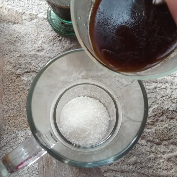 Siapkan gelas saji, isi dengan gula. Tuang kopi ke dalam gelas saji, lalu aduk rata hingga gula larut