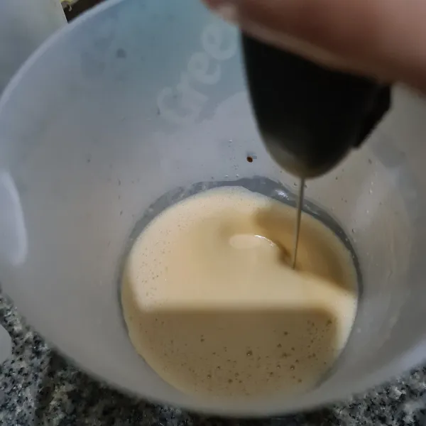 Kocok kopi menggunakan milk frother hingga berbusa.