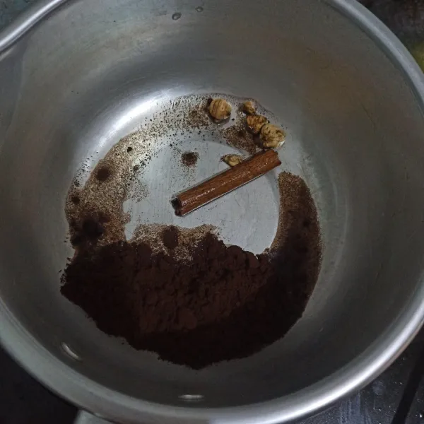 Tuang kopi ke dalam panci, beri kapulaga dan kayu manis.