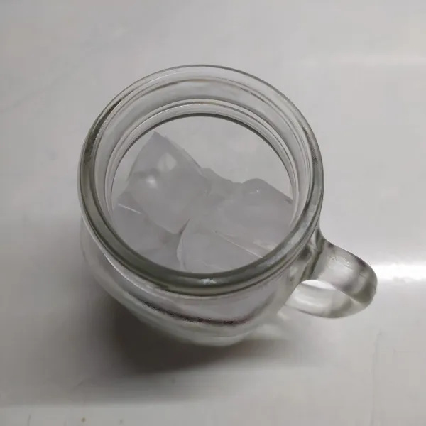 Ambil gelas saji, beri es batu ke dalam gelas.