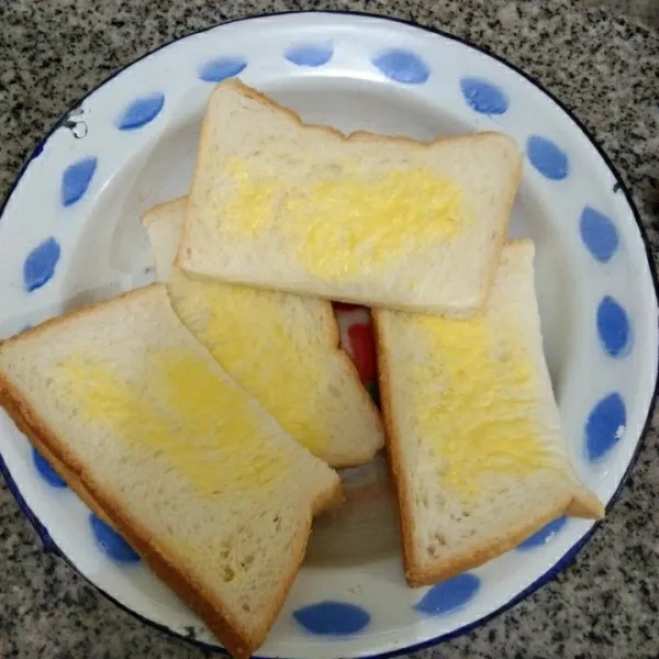 Belah roti menjadi 2 bagian, lalu olesi dengan butter/margarin secukupnya.