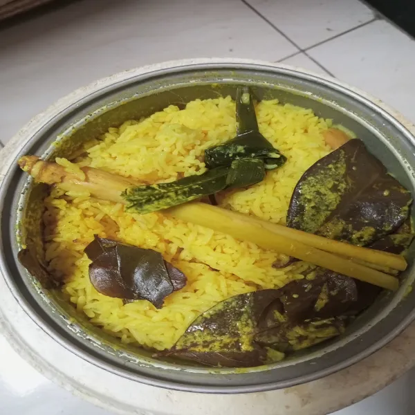 Masak nasi kuning seperti masak nasi biasa, setelah matang aduk rata.