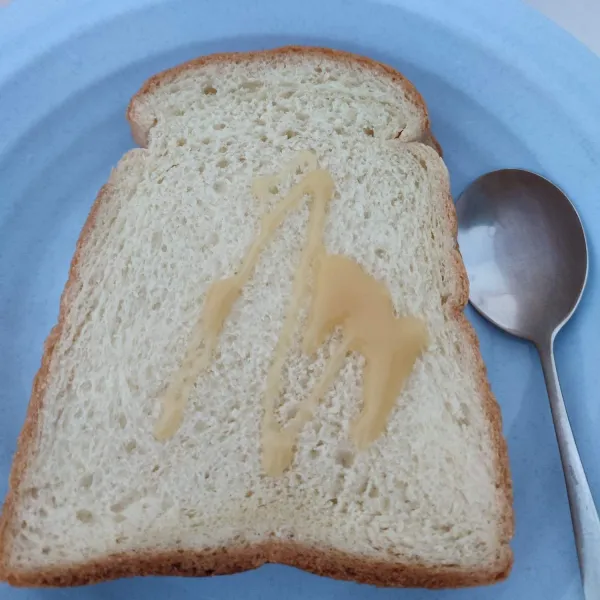 Oles roti tawar dengan susu kental manis sampai rata, kemudian tumpuk.
