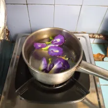 Tuang air ke dalam panci, lalu masukkan bunga telang.