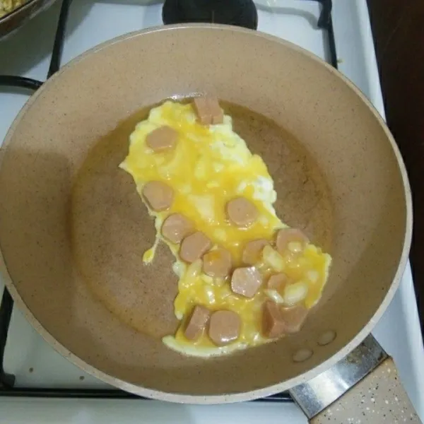 Panaskan margarin, lalu tuang setengah adonan telur.
