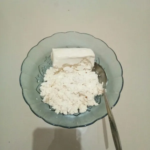 Masukkan tahu ke dalam mangkok, lalu hancurkan dengan sendok.