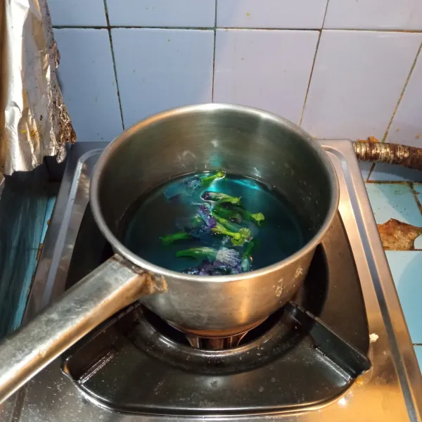 Rebus bunga telang sampai berubah warna airnya, lalu matikan api dan biarkan dingin.