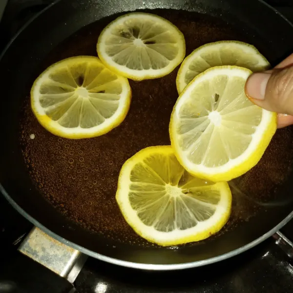 Setelah mendidih tambahkan pewarna kuning, lalu aduk merata. Kemudian masukkan potongan lemon.