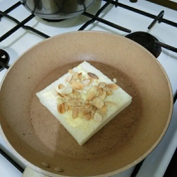 Beri kacang almond di atasnya, kemudian balikkan roti. Panggang hingga roti berubah warna.