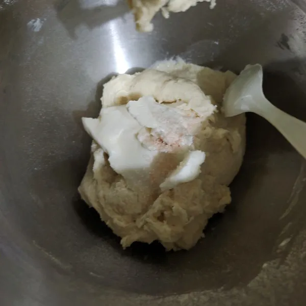 Tambahkan mentega putih dan garam, lalu uleni lagi hingga adonan terasa lebih kalis dan lembut.
