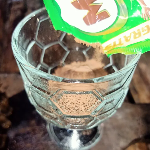 Cara membuat milo dinosaur : Masukkan 1/2 sachet milo ke dalam gelas.