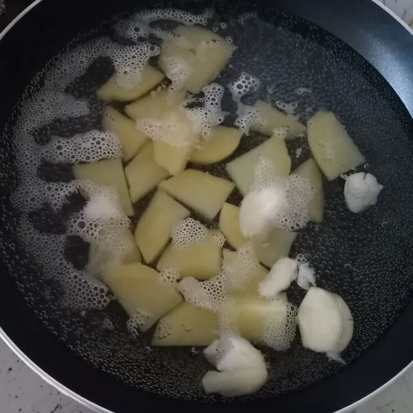 Didihkan air, rebus kentang dan bawang putih sampai mendidih lagi.