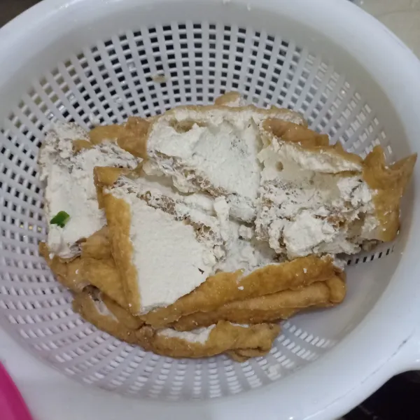 Kerat tahu lalu balik, keluarkan isinya.