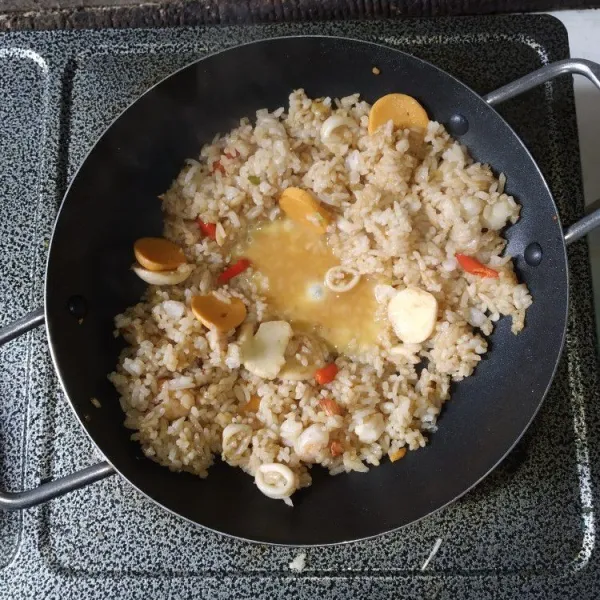 Buat ruang ditengah wajan, kocok lepas telur, masukkan kedalam nasi goreng, aduk rata hingga telur matang.