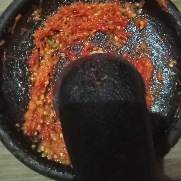 Goreng cabai rawit, cabai merah, dan bawang putih hingga layu. Pindahkan ke cobek, ulek hingga halus, lalu tambahkan tomat. Ulek kasar saja.