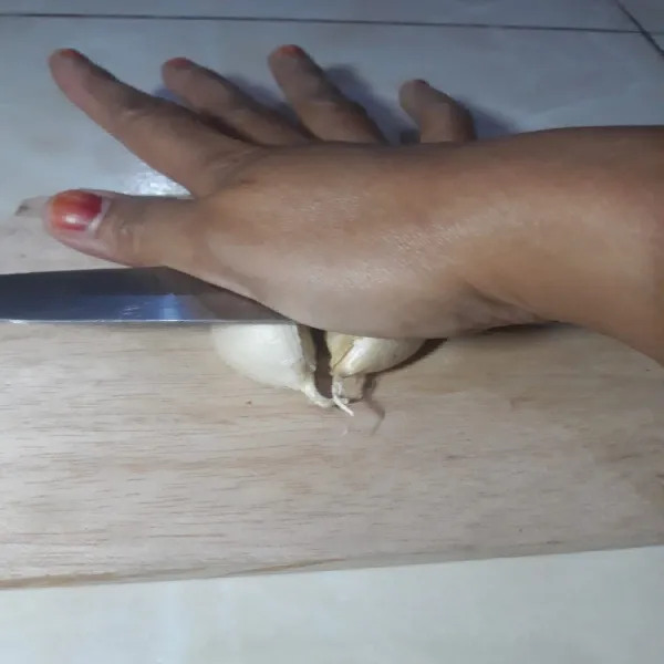 Tekan pisau hingga berbunyi "krek". Kulit bawang akan terlepas dari buahnya.