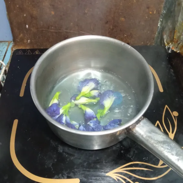 Masukkan air dan bunga telang ke dalam panci, lalu didihkan sampai air berubah warna. Kemudian sisihkan.