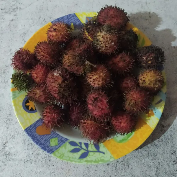 Siapkan buah rambutan tanpa tangkai, lalu kupas kulitnya.