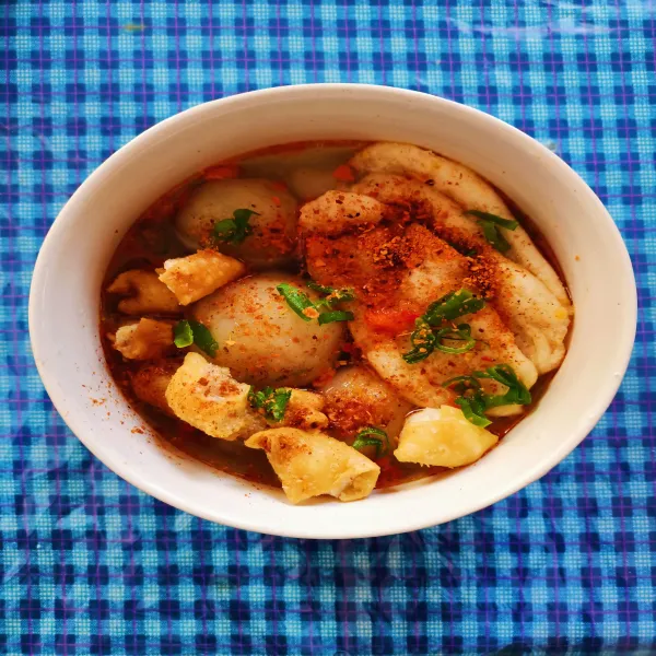 Masukkan cilok, lidah cuangki, dan siomay kering, lalu tambahkan kuah dan sambal yang telah di tumis. Taburkan daun bawang dan bubuk cabe kering.