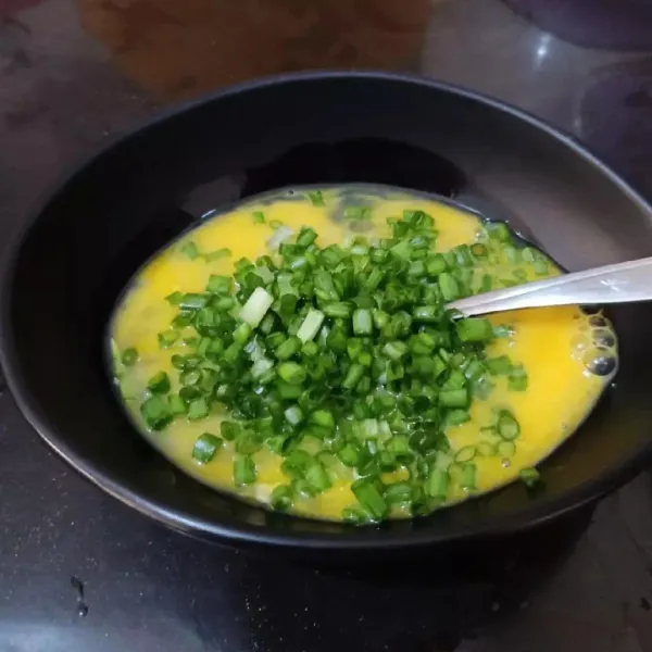 Tuang telur ke dalam mangkuk, tambahkan kecap asin, kaldu jamur, susu cair, dan irisan daun bawang, lalu aduk rata.
