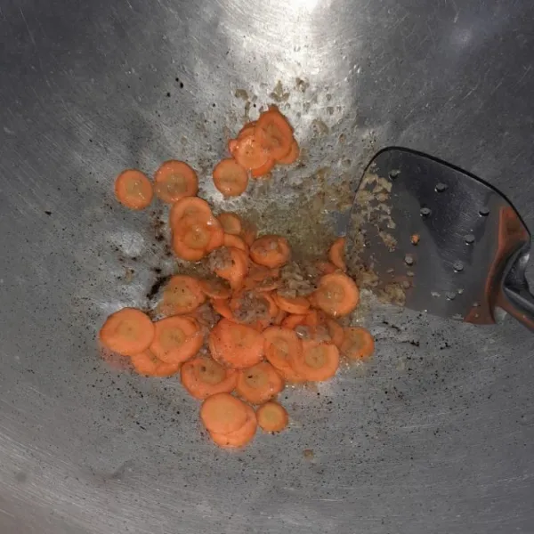 Panaskan minyak goreng, tumis bumbu hingga harum. Lalu masukkan wortel, garam, kaldu bubuk, dan air. Tumis wortel hingga setengah matang.