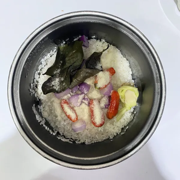 Cuci beras, masukkan kedalam rice cooker bersama daun salam, serai, cabe rawit, bawang merah dan kaldu bubuk rasa ayam.