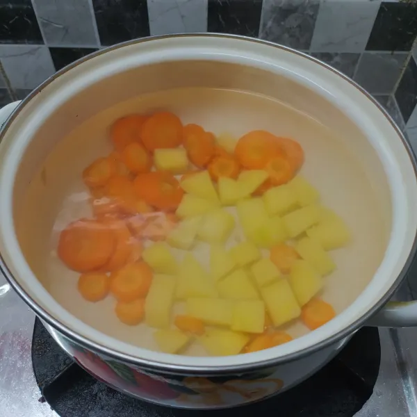 Rebus air sampai mendidih, masukkan kentang dan wortel. Masak sampai ½ matang.