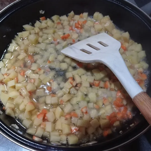 Masukkan kentang dan wortel, aduk rata lalu tuang air, bumbui garam, gula pasir dan lada bubuk. Masak sampai setengah matang.