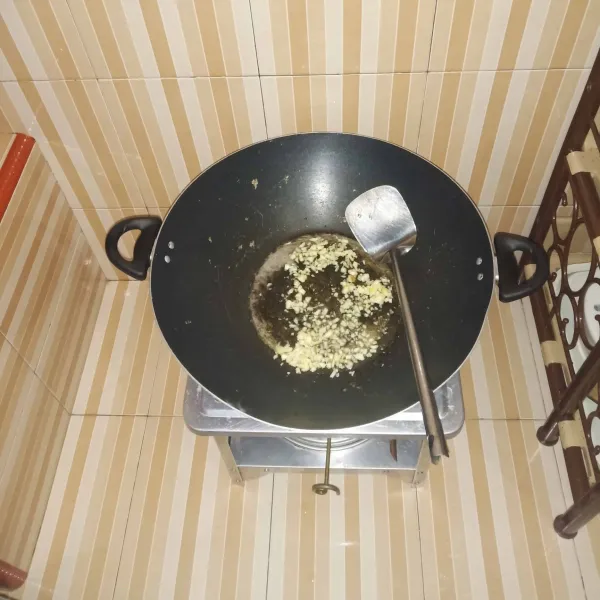 Panaskan minyak goreng, lalu goreng bawang putih hingga harum dan kuning keemasan, lalu angkat dan tiriskan.