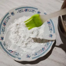 Masukkan tepung tapioka, baking soda, vanili bubuk, dan garam ke dalam piring, lalu aduk rata. Beri percikan air panas dengan bantuan kuas.