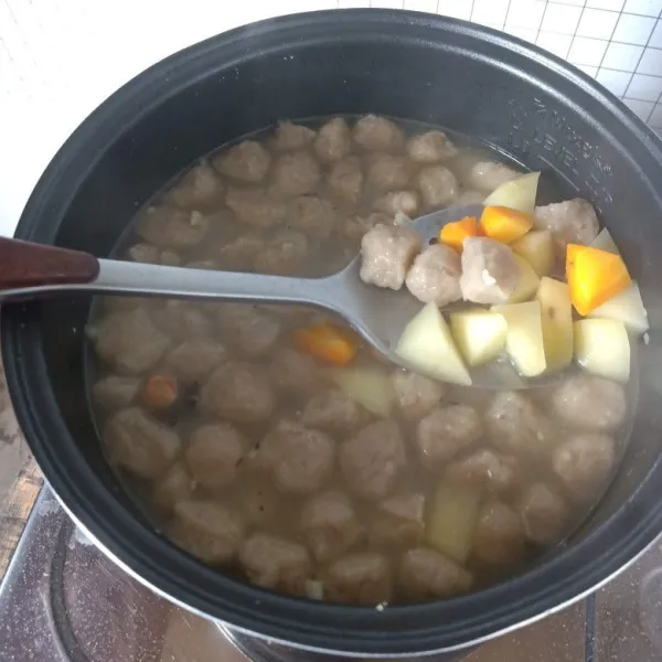 Masukkan kentang sekitar 5 menit, lalu wortel, kemudian bakso. Beri garam dan kaldu bubuk, aduk merata dan tunggu hingga matang.