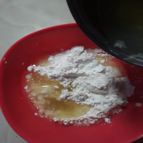 Masukkan air rebusan bawang ke dalam adonan tepung sedikit demi sedikit.