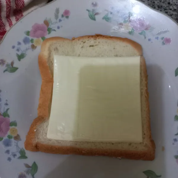 Tata lembaran keju di bagian tengah roti.