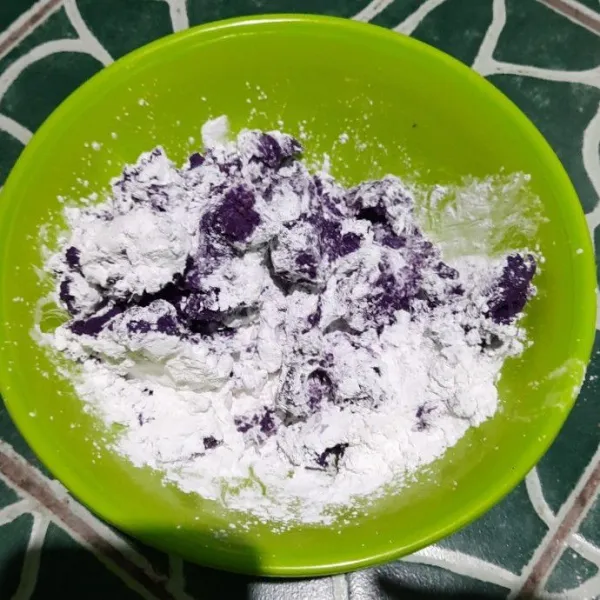 Tambahkan tepung tapioka, gula pasir ke dalam mangkuk ubi ungu, aduk rata hingga bisa di bentuk.