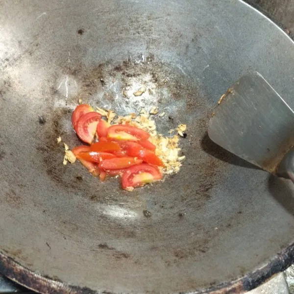 Tumis bawang putih hingga harum dan masukkan irisan tomat, lalu tambahkan sedikit air.