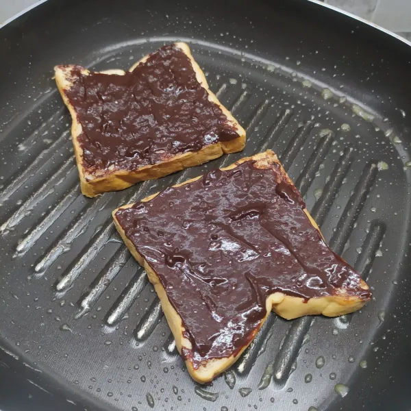 Panaskan grill pan, beri sedikit margarin sampai meleleh. Panggang roti dengan posisi selai coklat di bagian atas.