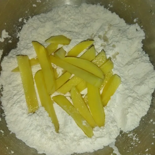 Lalu masukkan potongan kentang secukupnya untuk 1 kali goreng, aduk dengan menggunakan kedua tangan, hingga kentang dilapisi tepung.
