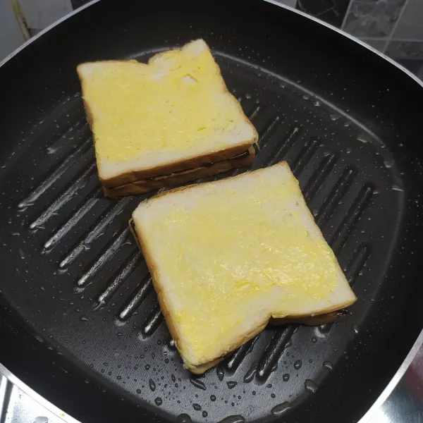 Ambil roti tawar yang sudah dioles margarin salah satu sisinya. Tutup di atas roti yang dioles selai coklat, tunggu sampai bagian bawah kecoklatan.