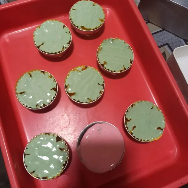 Siapkan cup bolu kukus. Kemudian isi secara bergantian dari putih, pink, lalu hijau sampai cup penuh.